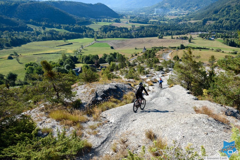 2 vététistes vus de dos dans une descente sur les schistes avec vue grandiose sur la montagne